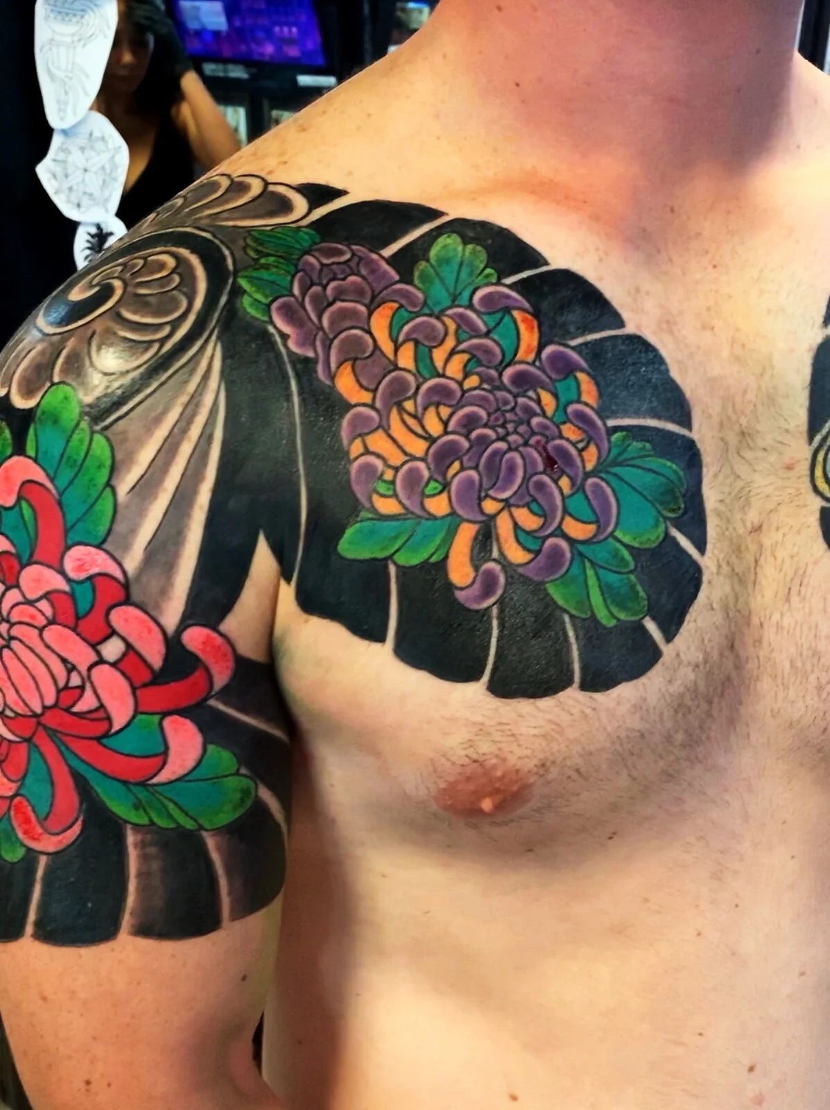 Japanese Wabori chrysanthemum chest panel tattoo with purple, orange, and pink color by Tim Goodrich, Waikiki, Hawaii